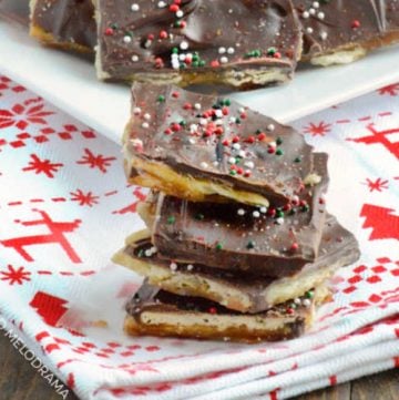 easy saltine toffee christmas crack with sprinkles stacked on a holiday towel