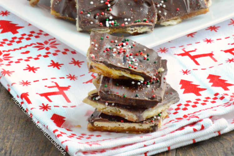 easy saltine toffee christmas crack with sprinkles stacked on a holiday towel