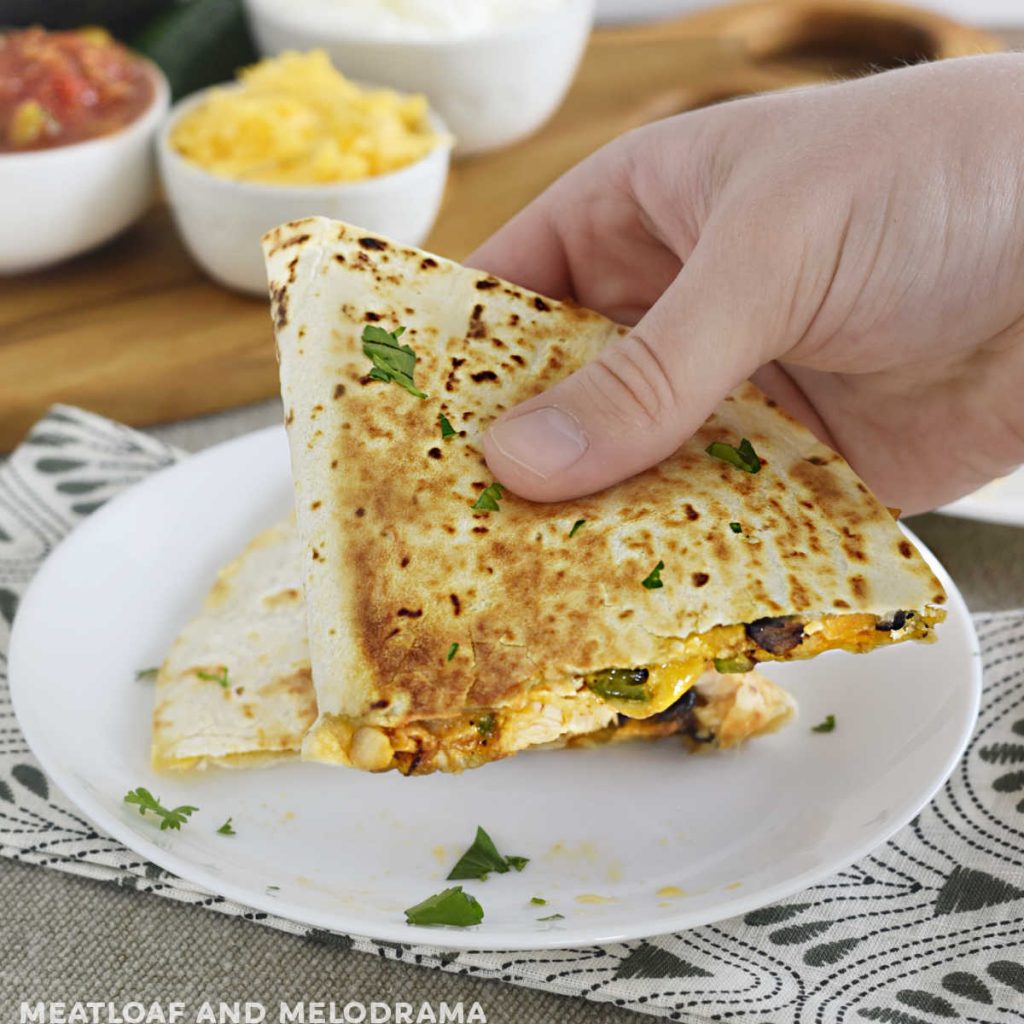 hand holding chicken black bean quesadilla with melty cheese