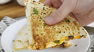 hand holding chicken black bean quesadilla with melty cheese