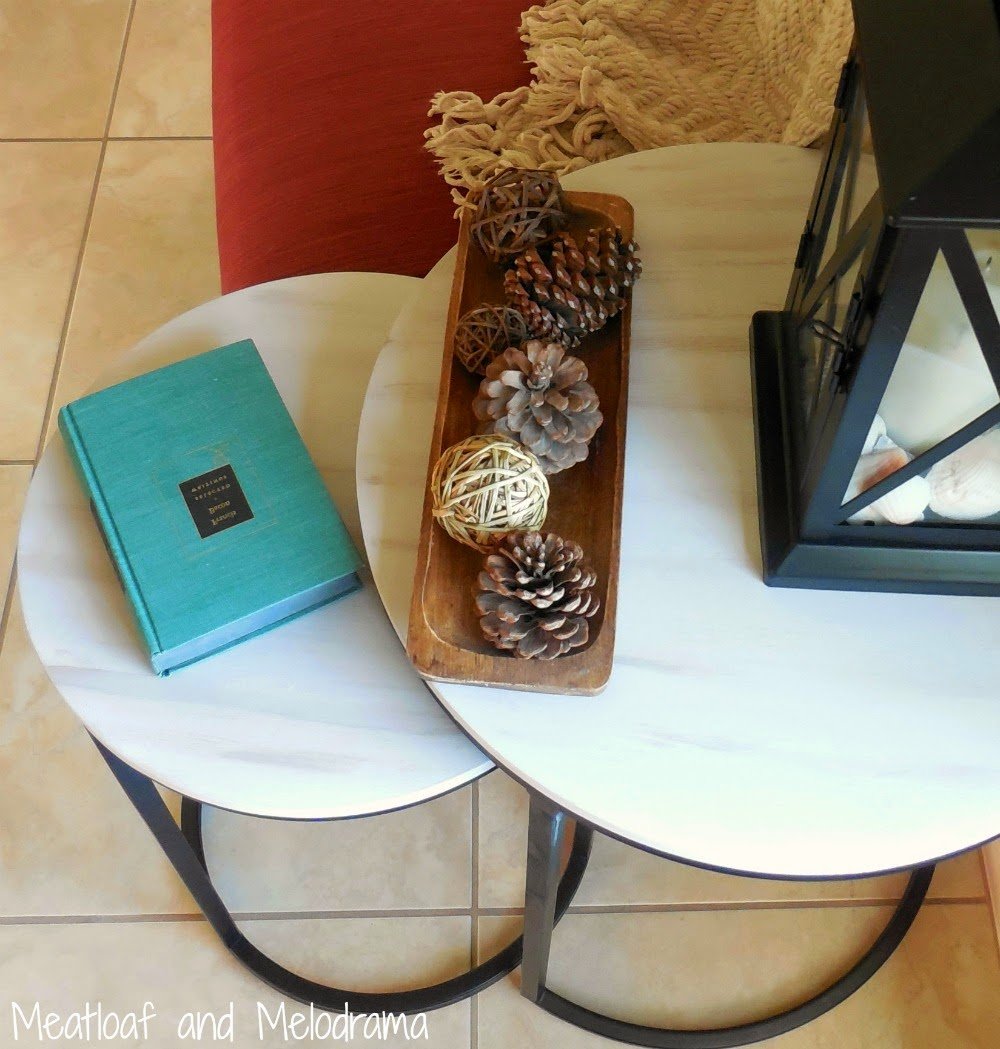 round industrial side tables painted grey and brown with lantern and pinecones