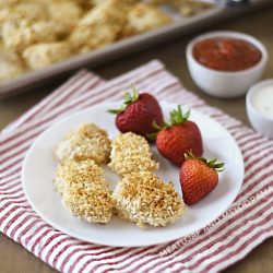 baked homemade chicken nuggets with panko on a white plate with strawberries