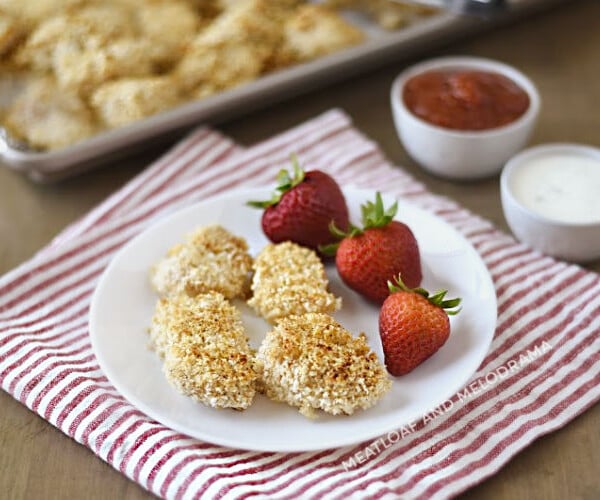 baked homemade chicken nuggets with panko on a white plate with strawberries