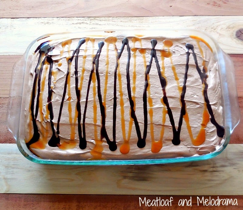 chocolate caramel poke cake in a glass baking dish with chocolate cool whip frosting