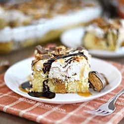 slice of butterfinger poke cake with cool whip frosting on a white platel