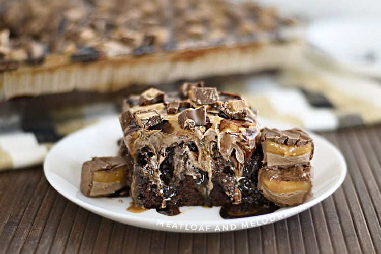 milky way poke cake on a white plate with milky way candy bars