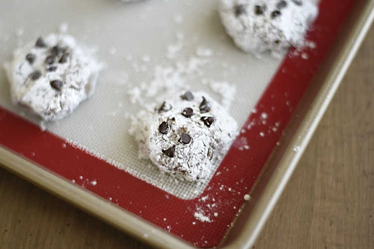 chocolate cool whip cookies with powdered sugar and mini chocolate chips on baking sheet