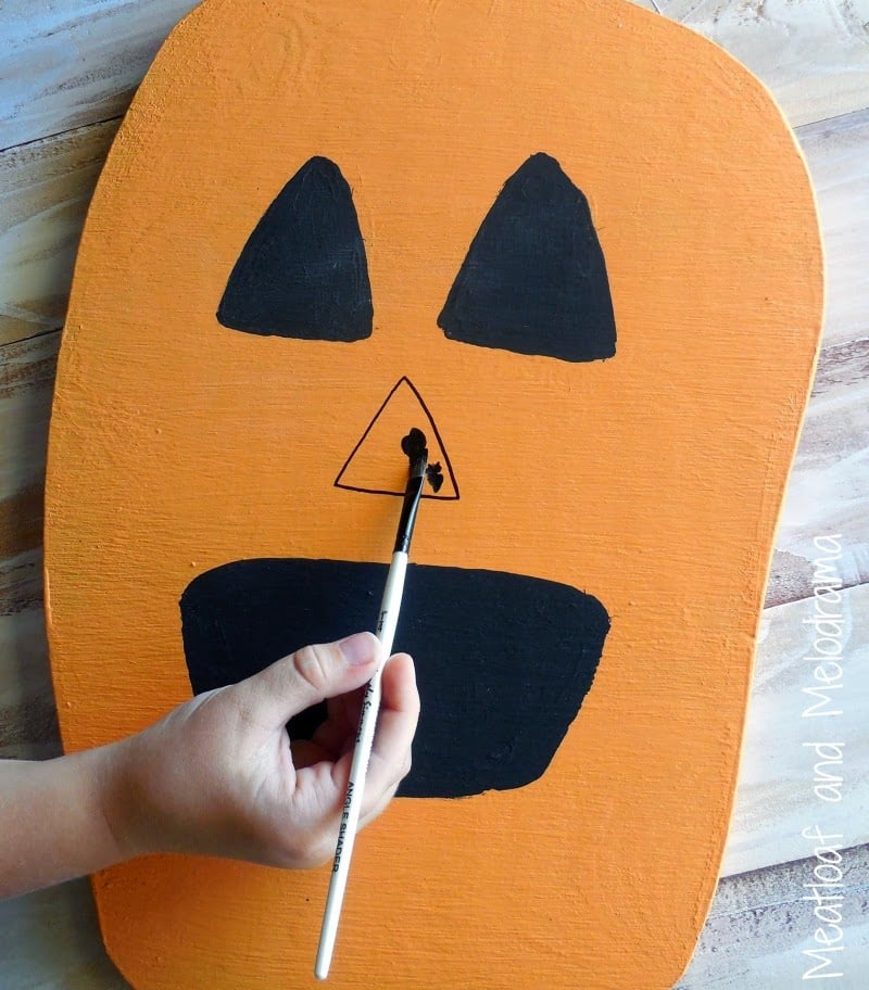 painting face on wood pumpkin