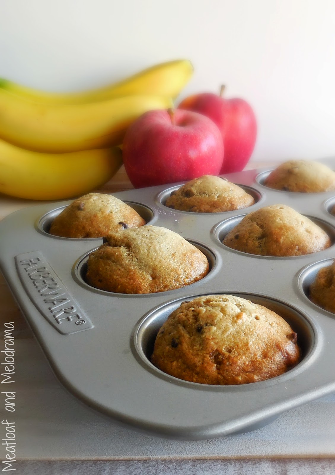 banana applesauce muffins in muffin pan with bananas and apples