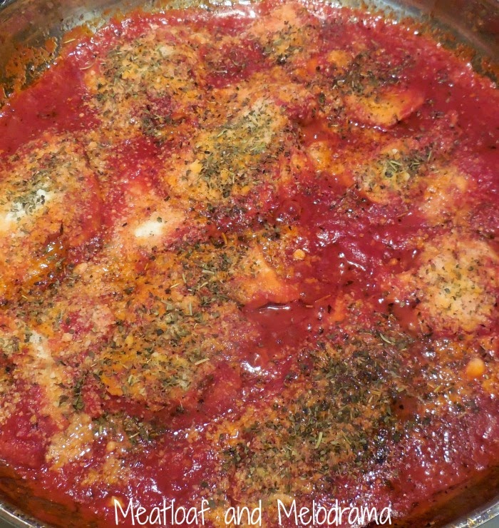 cook chicken breasts in red sauce with herbs in skillet