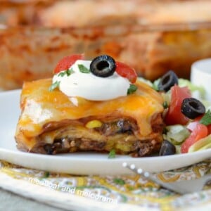 southwestern lasagna enchilada casserole on plate with sour cream lettuce tomatoes and olives