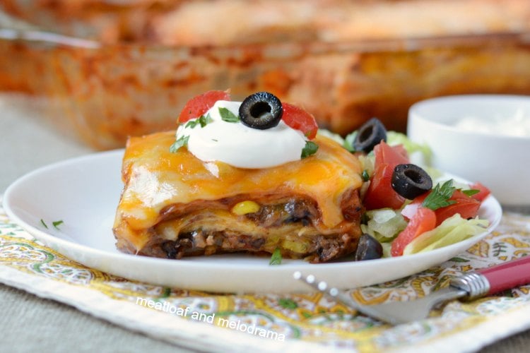 southwestern lasagna enchilada casserole on plate with sour cream lettuce tomatoes and olives