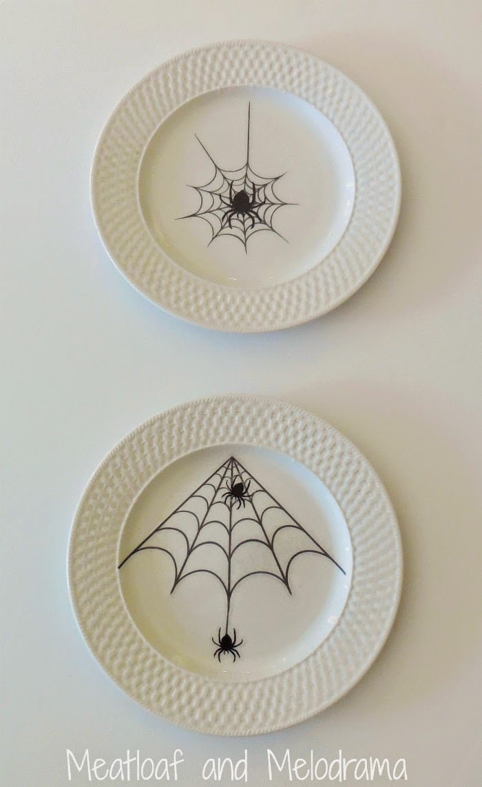 two white plates with black spider web window clings for halloween