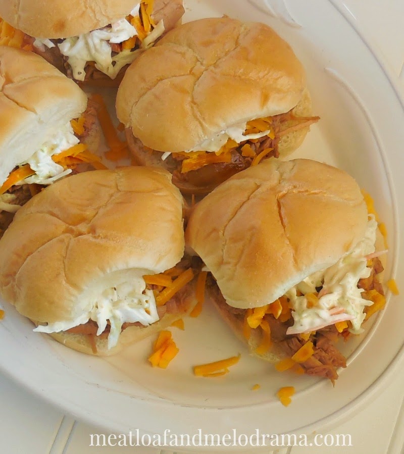 slow cooker barbecue pork sliders with cheddar cheese and coleslaw on a platter for game day