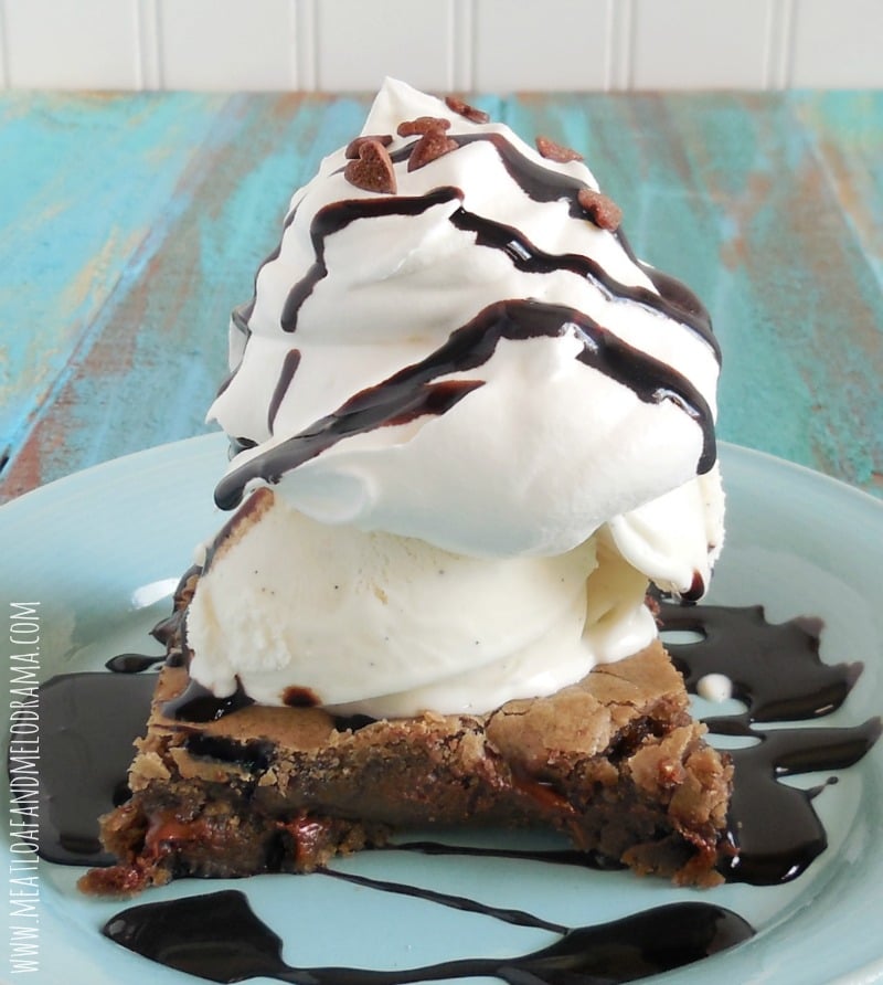 chocolate cookie bar topped with vanilla ice cream and whipped cream and chocolate sauce 