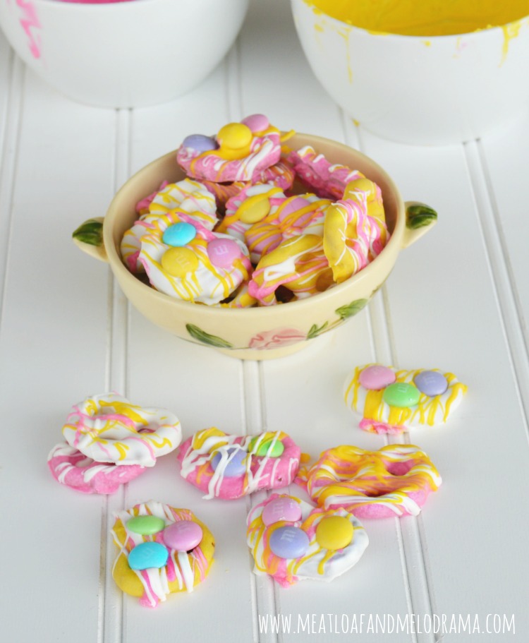 a bowl of pink and yellow and white candy coated pretzels with m and ms