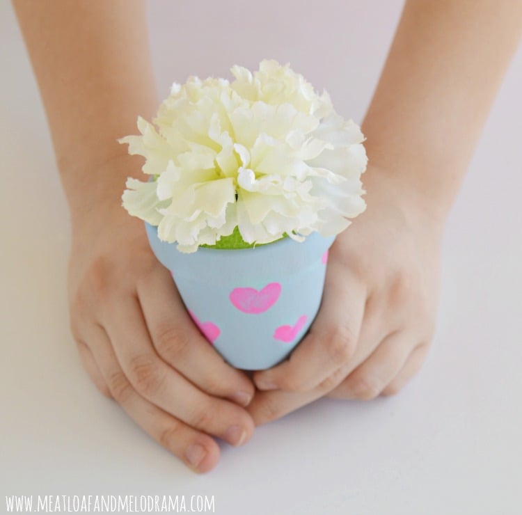 girl holding decorated flower pot with hearts and flower
