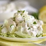 lemon chicken salad with apples over lettuce on a white plate