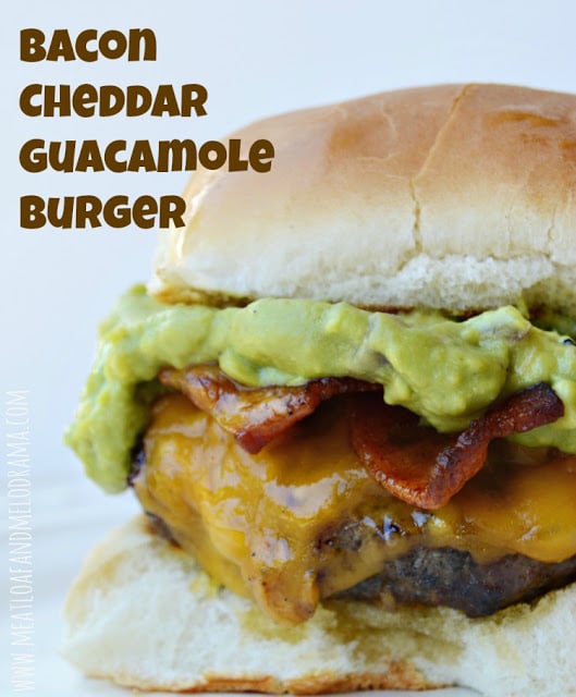 Hamburger topped with cheddar cheese, guacamole and bacon on a bun