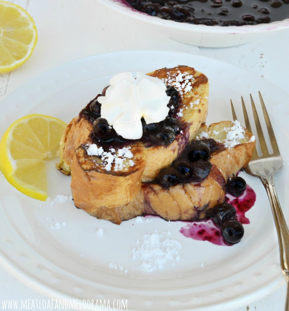 french toast slices topped with blueberry sauce and powdered sugar and lemon