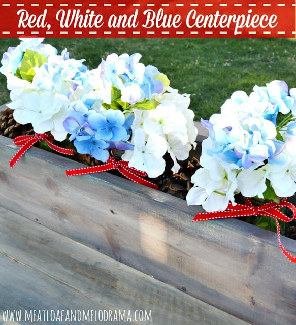 rustic wood box filled with white and blue flowers with red ribbon