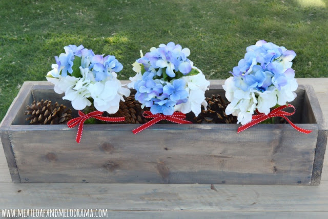 white and blue faux hydrangeas in glass bottles with red ribbon