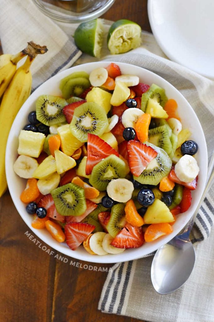 cut up summer fruit in a white serving bowl