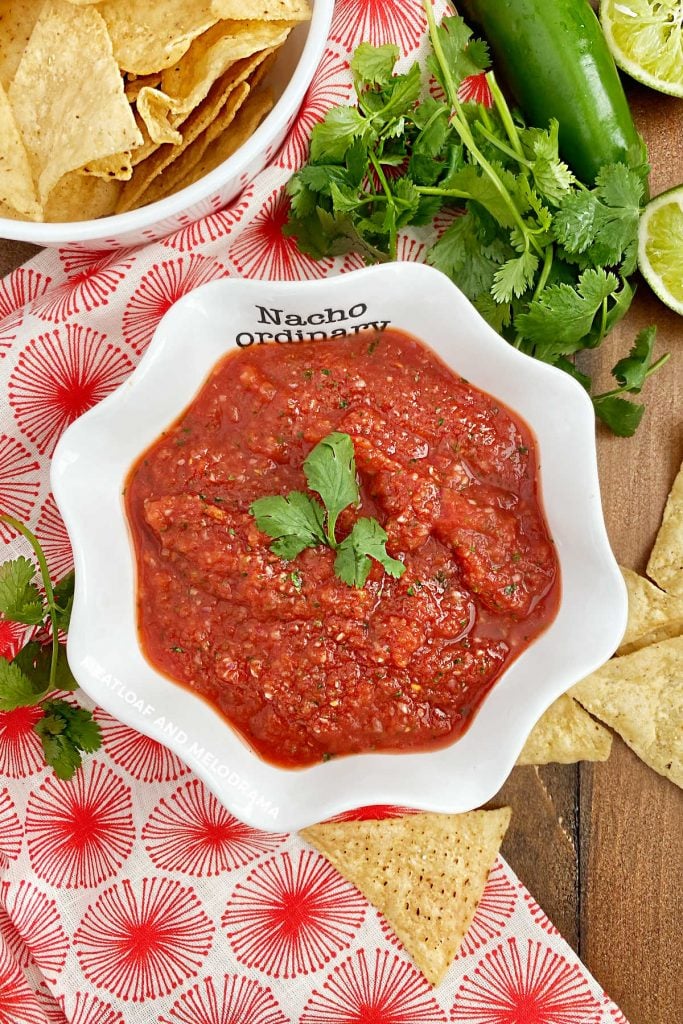 overhead view of homemade blender salsa in a white serving dish with cilantro and chips