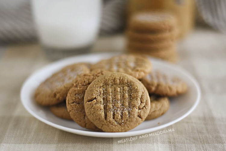 flourless peanut butter cookies on a white plate with glass of milk 