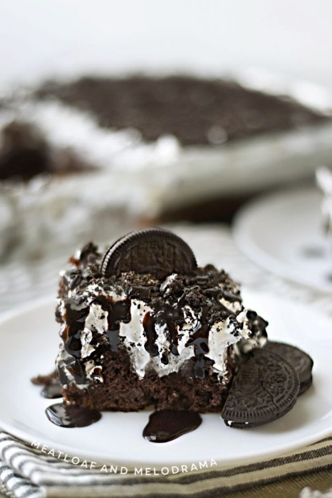 oreo poke cake dessert on white plate with oreos and chocolate syrup