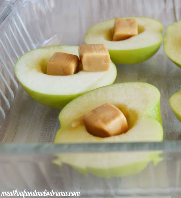 cut apples with center scooped out and caramel candy in the middle