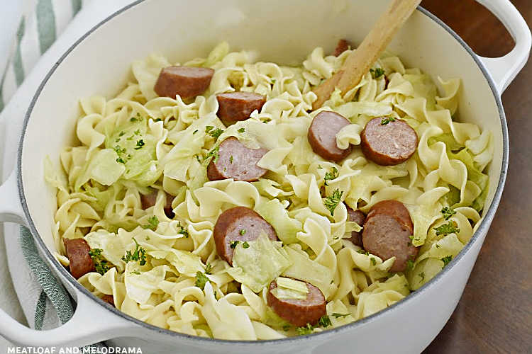 haluski and kielbasa, fried cabbage with noodles and smoked sausage in a white dutch oven