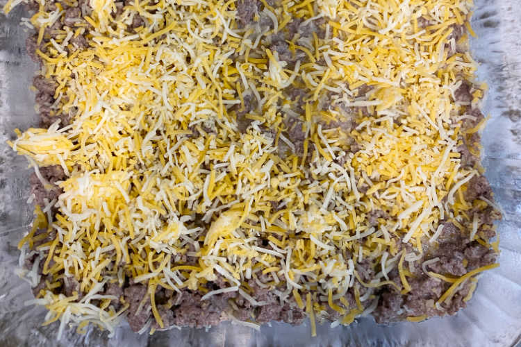 cooked hamburger meat and shredded cheese in a baking dish