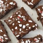 overhead view of sliced peppermint brownies with chocolate and crushed peppermint candies on white marble