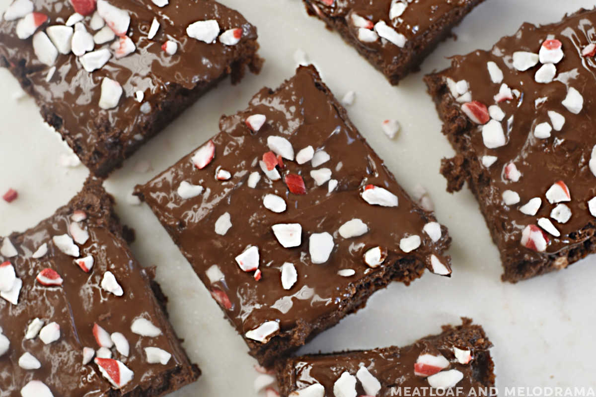 overhead view of sliced peppermint brownies with chocolate and crushed peppermint candies on white marble