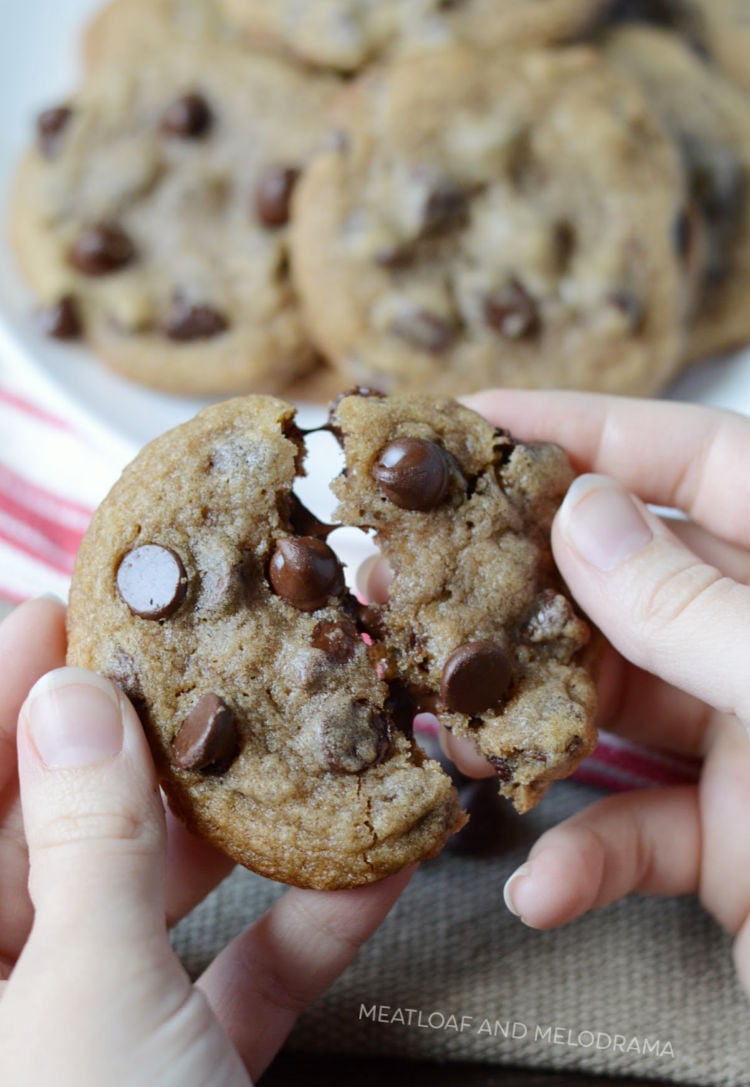 freshly baked cookie with melted chocolate morsels in hand.