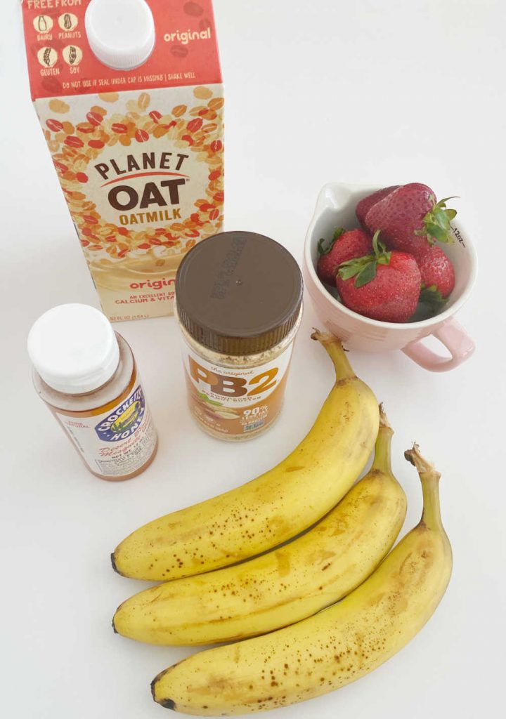 oat milk, pb 2, strawberries, bananas and honey on white surface