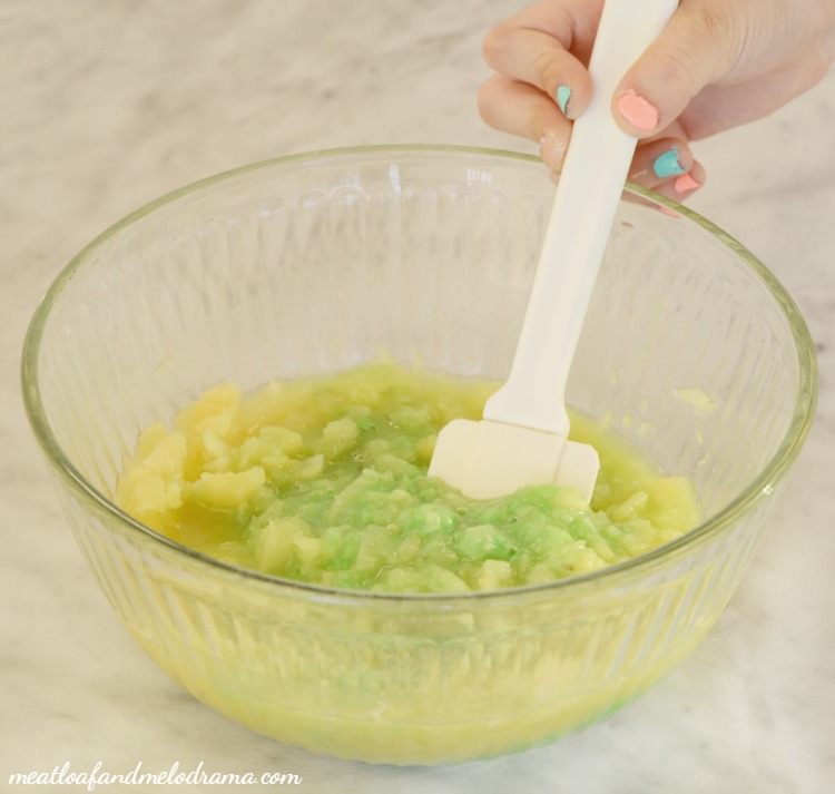 mix pineapples and pistachio pudding in glass mixing bowl with spatula