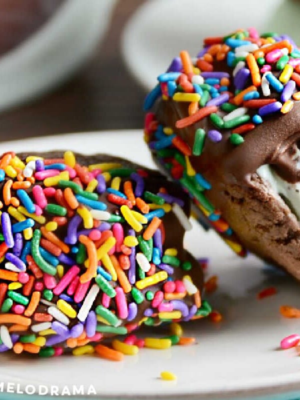 mint chocolate chip cookie ice cream sandwiches dipped in chocolate with sprinkles on plate