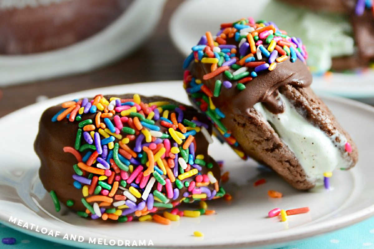 mint chocolate chip cookie ice cream sandwiches dipped in chocolate with sprinkles on a plate