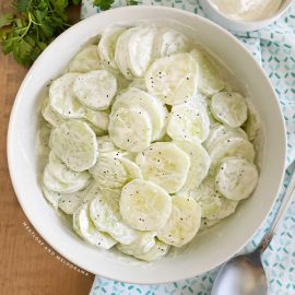creamy cucumber salad in a white serving bowl