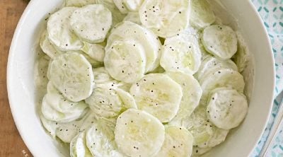 creamy cucumber salad with sour cream in a white serving bowl