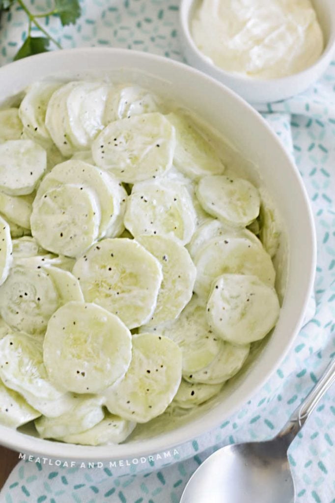 close up of sour cream cucumbers in a white bowl