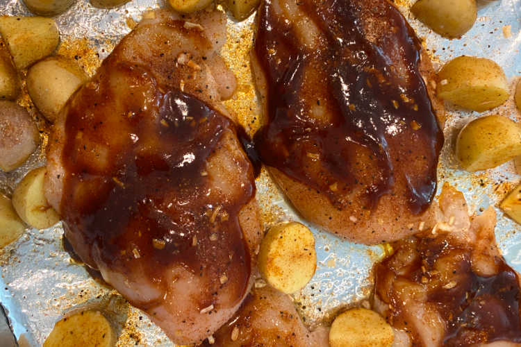 chicken breasts coated with bbq sauce on a baking sheet
