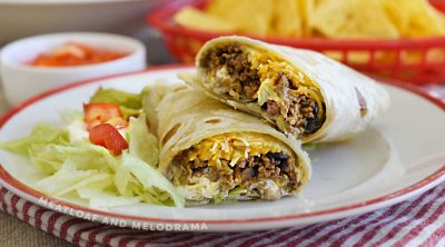 ground beef and black bean burritos with cheese, lettuce and tomatoes on plate