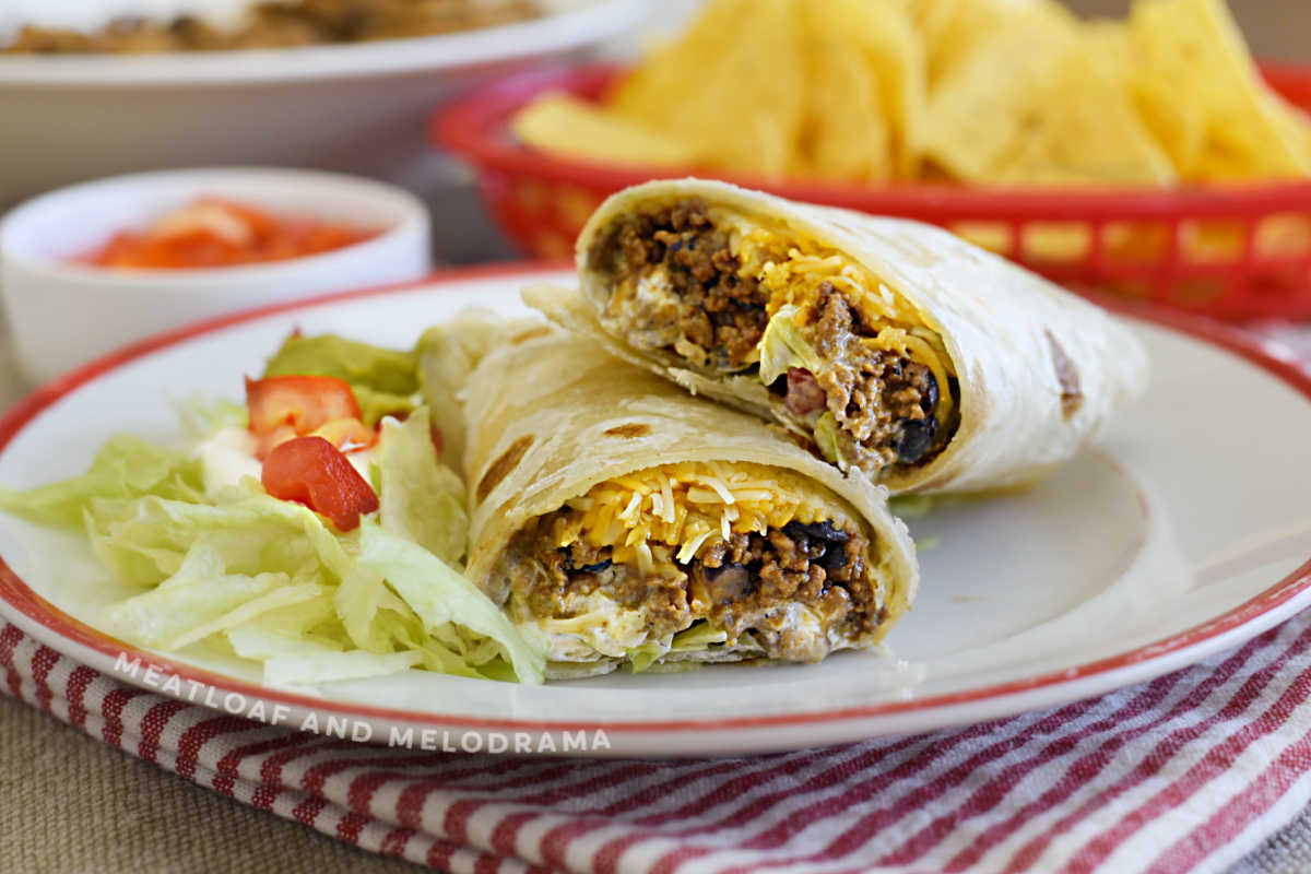 ground beef and black bean burritos with cheese, lettuce and tomatoes on plate