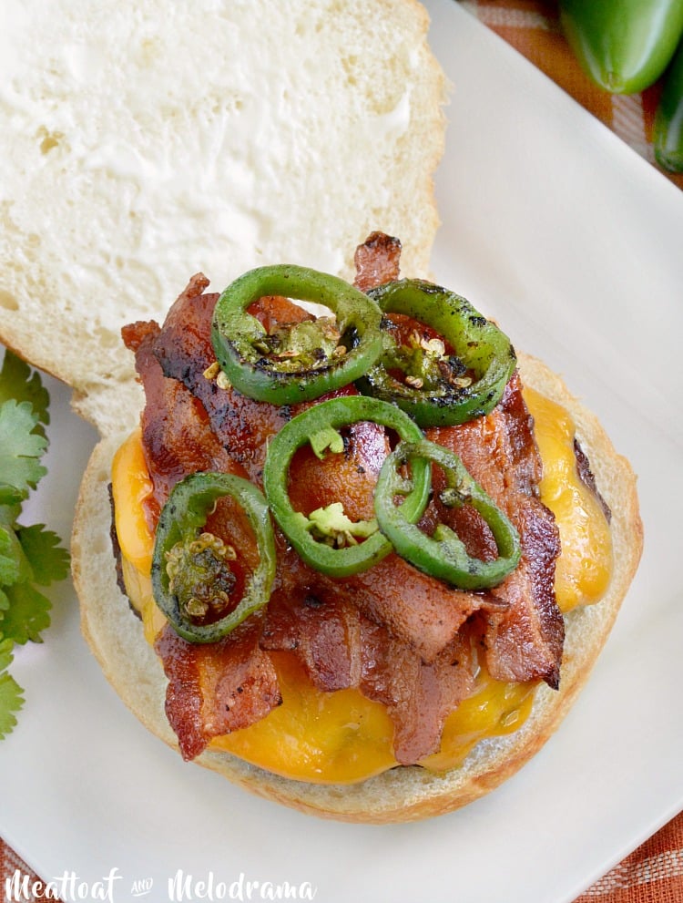 burger with cheddar cheese, bacon and sauteed jalapeno peppers on an an open bun