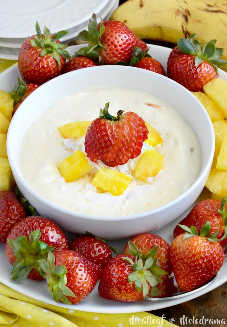 bowl of sour cream dip with fresh strawberries and pineapple