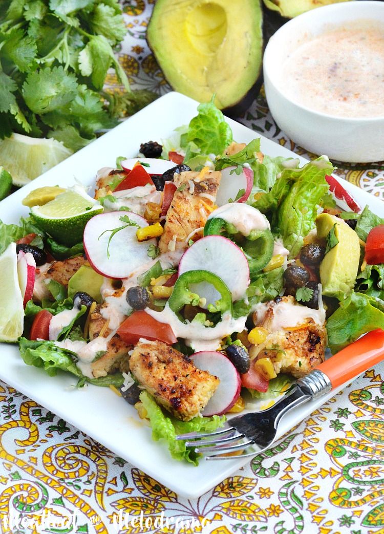loaded southwest chicken salad with avocados corn black beans and radishes on plate