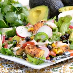 loaded southwest chicken salad with roasted corn and black beans over fresh greens